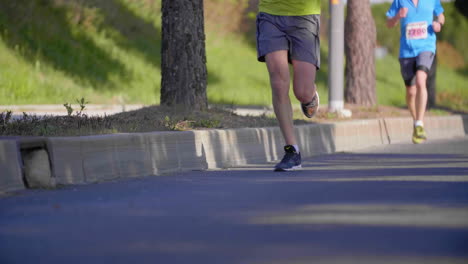 Blurry-to-focus-on-legs-from-runners-asphalt-road-with-trees
